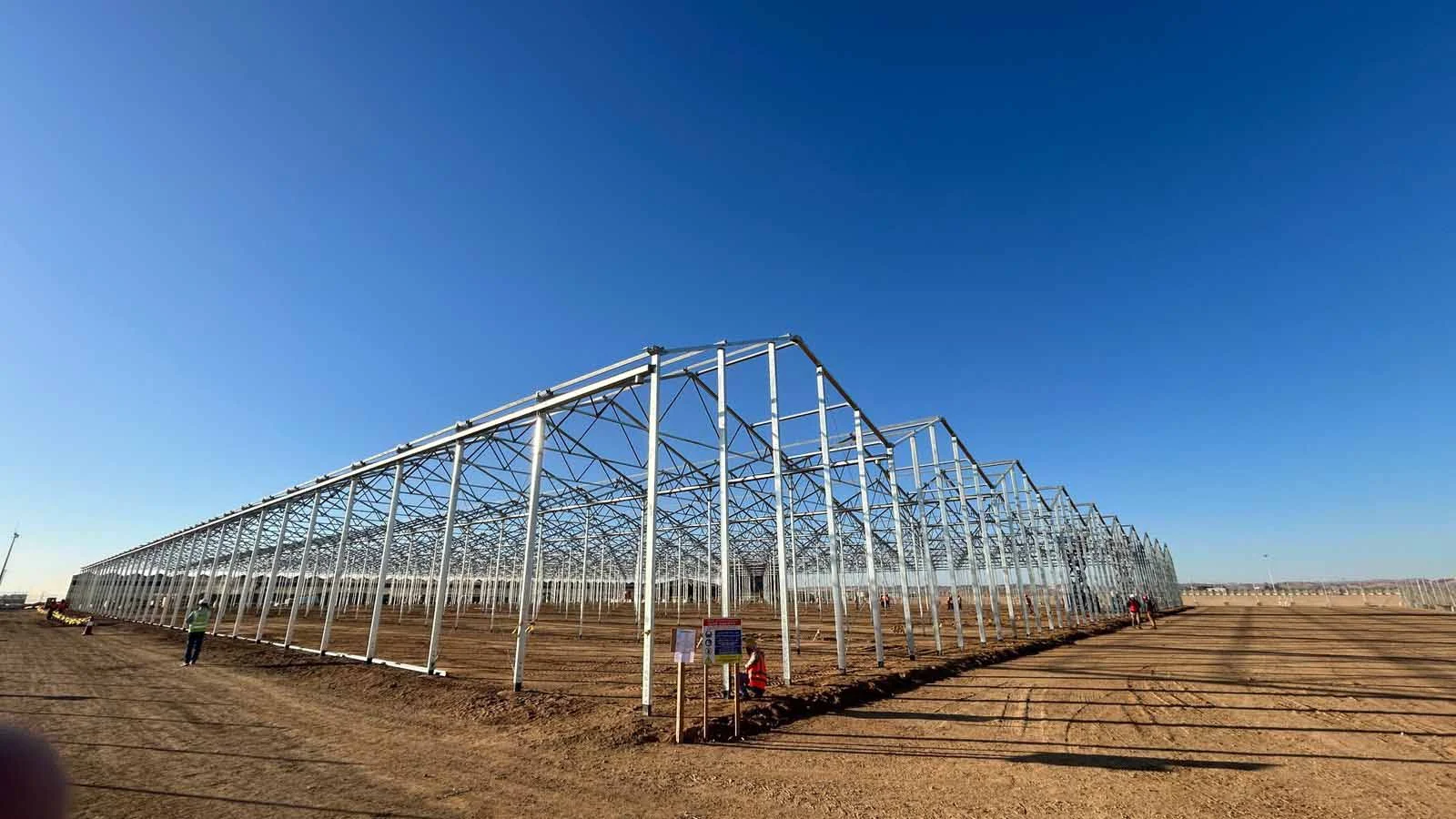 Large steel greenhouse frame erected on a desert site